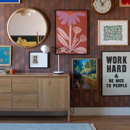 Isaac Desk Lamp on a wood credenza in a colorful room with patterned wallpaper and framed artwork
