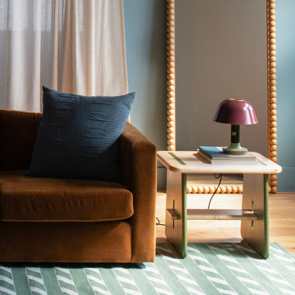 Angled view of the green Cotton Ladder Rug showcasing diagonal stripes beneath a sofa and side table