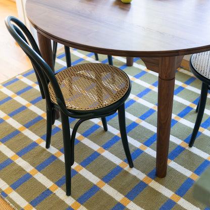 Close-up view of the Willard Dining Table showcasing its rounded edge and tapered legs with chairs on a patterned rug