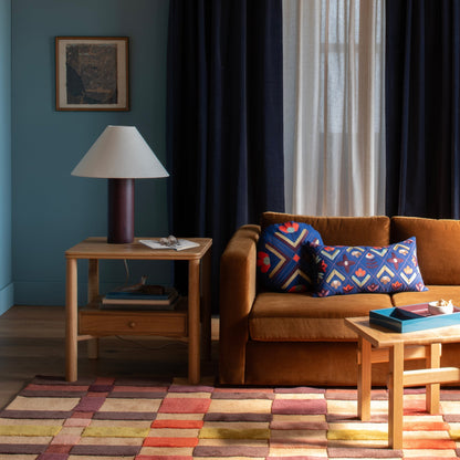 Campus Rug displayed in a colorful living room with a brown sofa, wood tables, and floor lamp