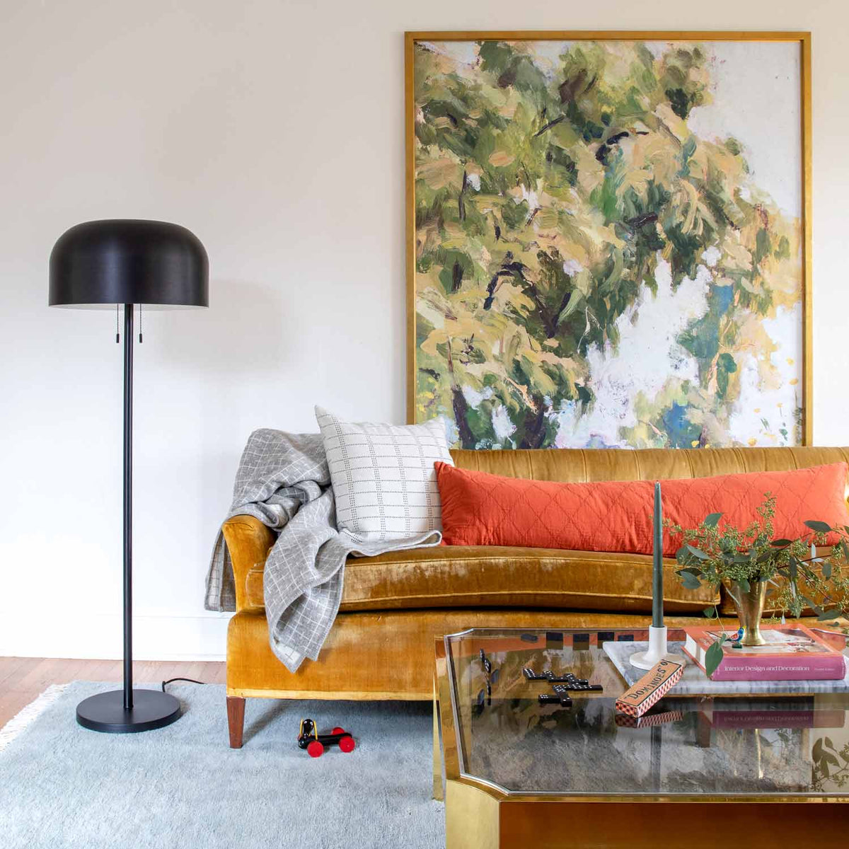 Grid Stitch Pillow Cover rests on a mustard sofa in a colorful living room with a floor lamp and artwork