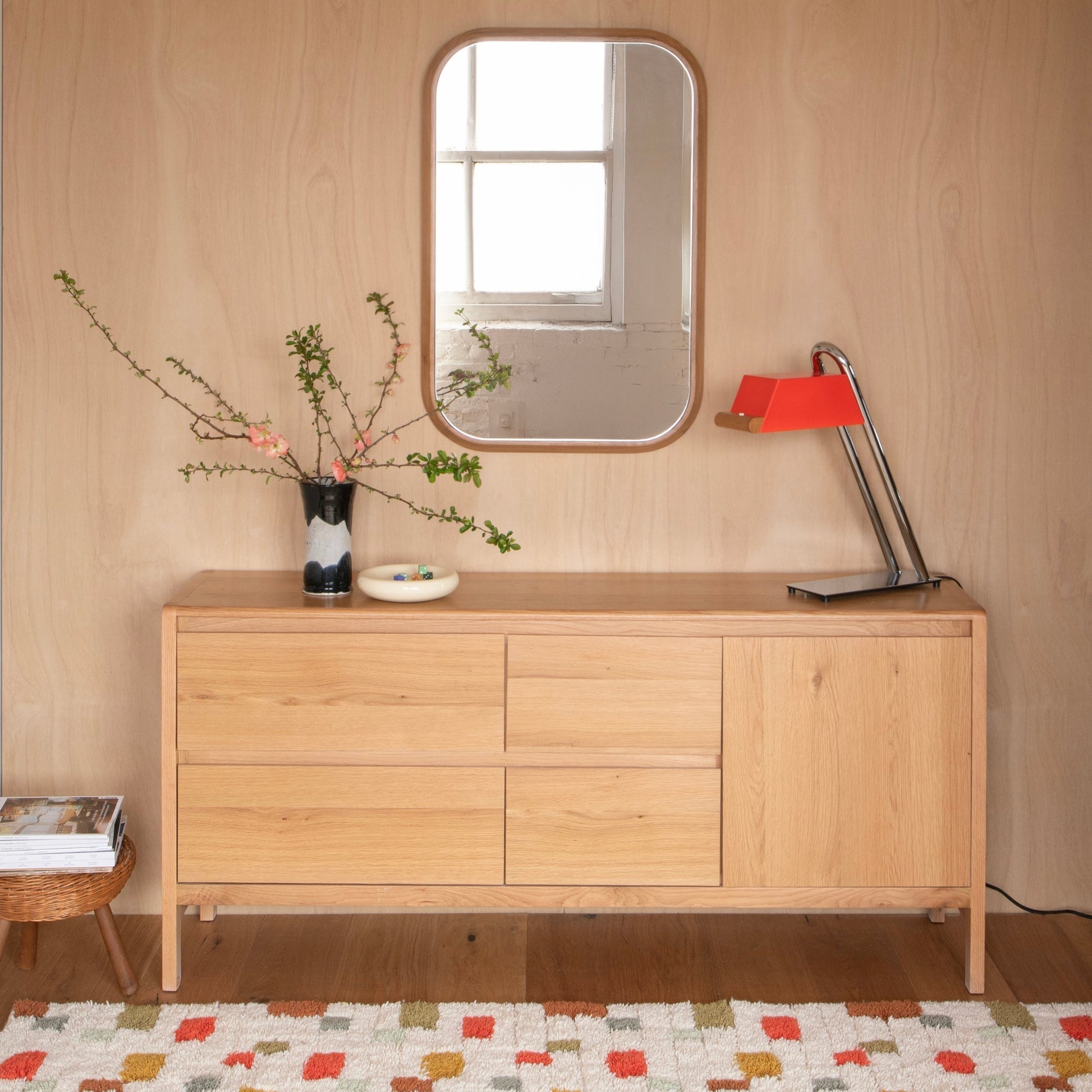 Pixel Handloom Shag Rug on hardwood floor in a styled room with a wooden dresser, rounded mirror, vase of flowering branches, and a red desk lamp