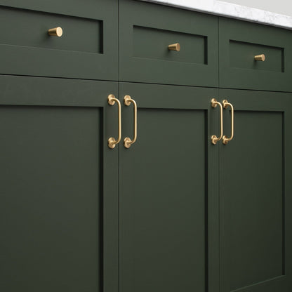 Close-up of Parker Pull showcasing brass hardware on dark green cabinetry