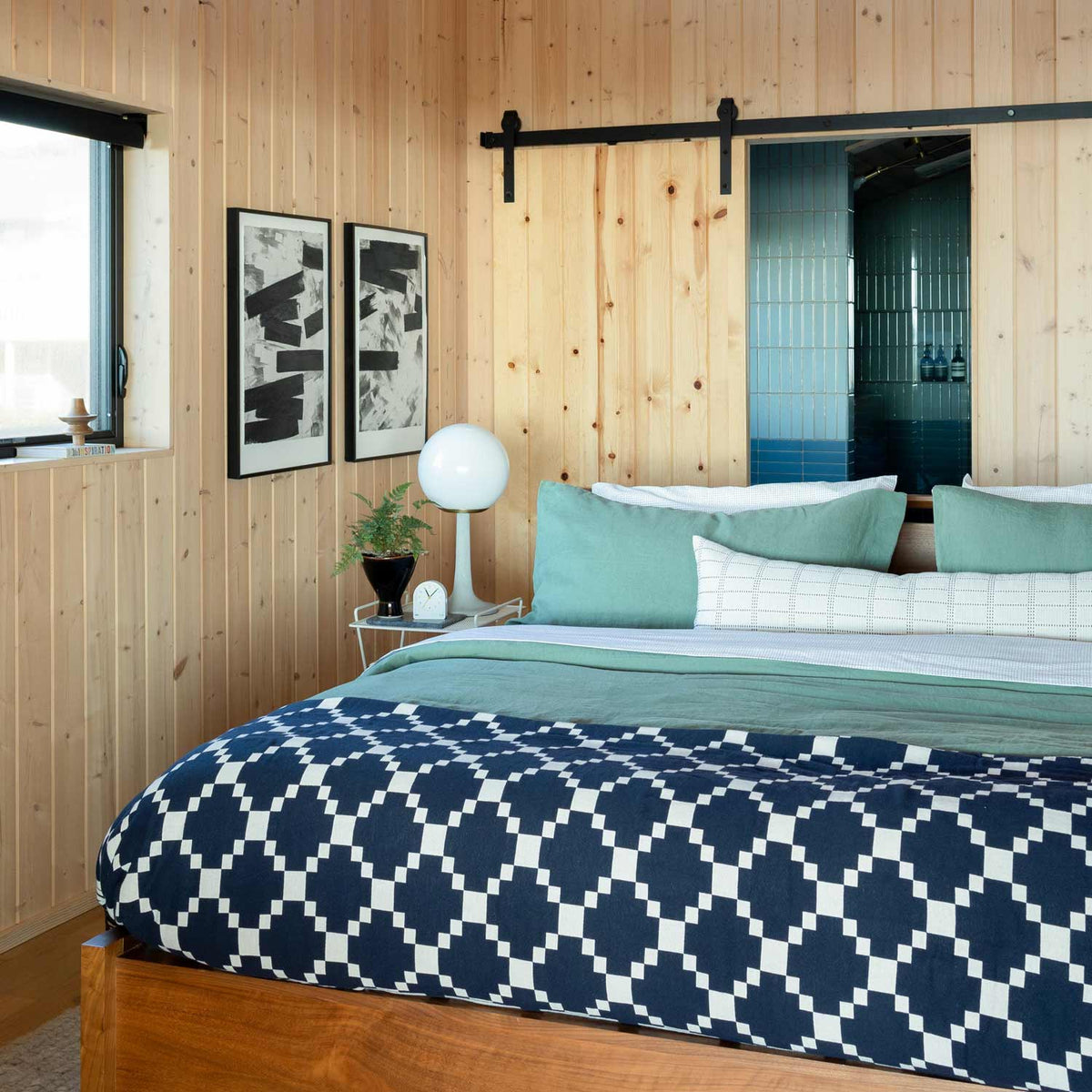 Grid Stitch Pillow Cover displayed on a bed in a wood-paneled bedroom