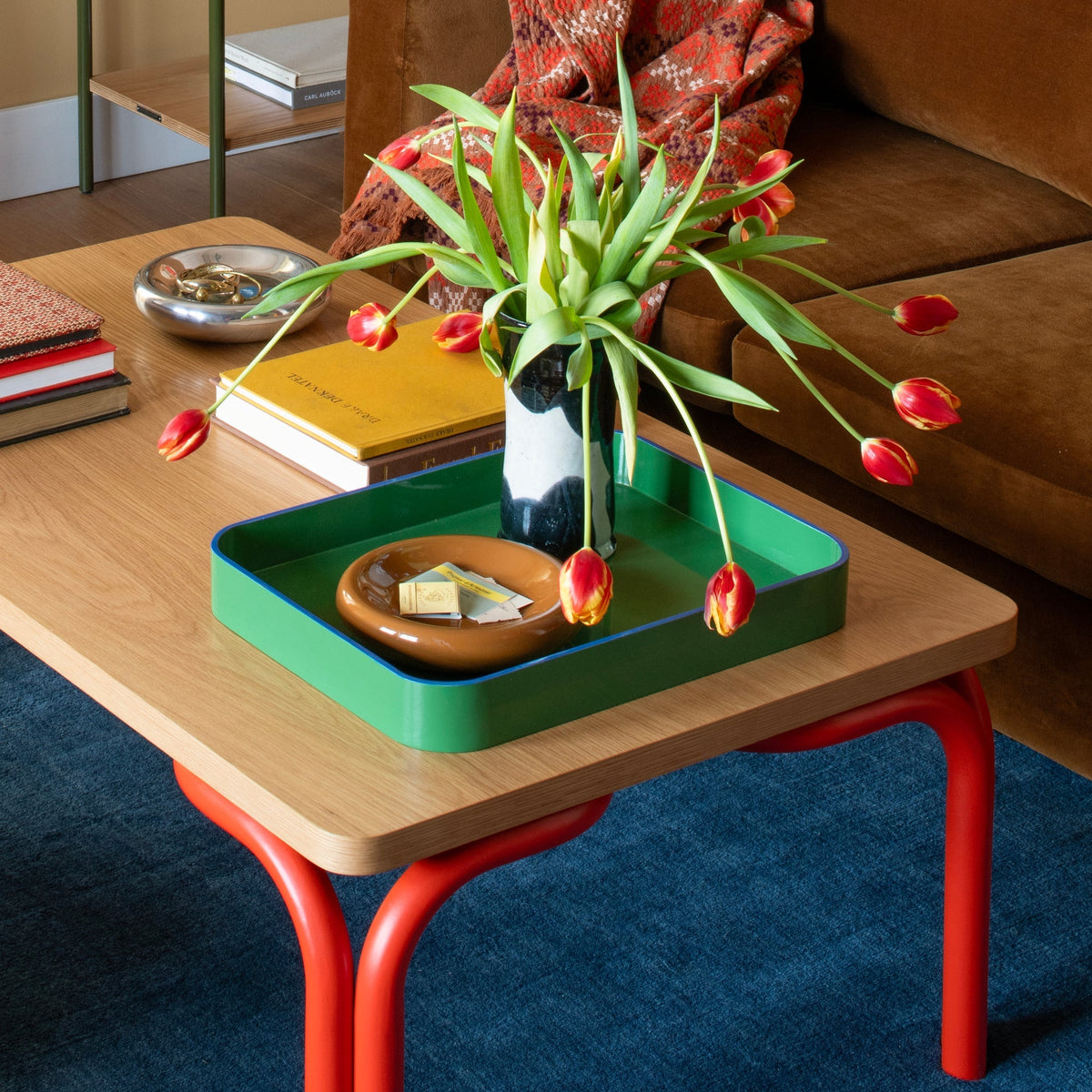 Green cast metal catch-all tray displaying a vase and dish on a coffee table
