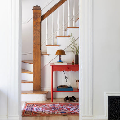 Pink Linnea wool flatweave rug with geometric motifs displayed in a bright hallway beneath a staircase
