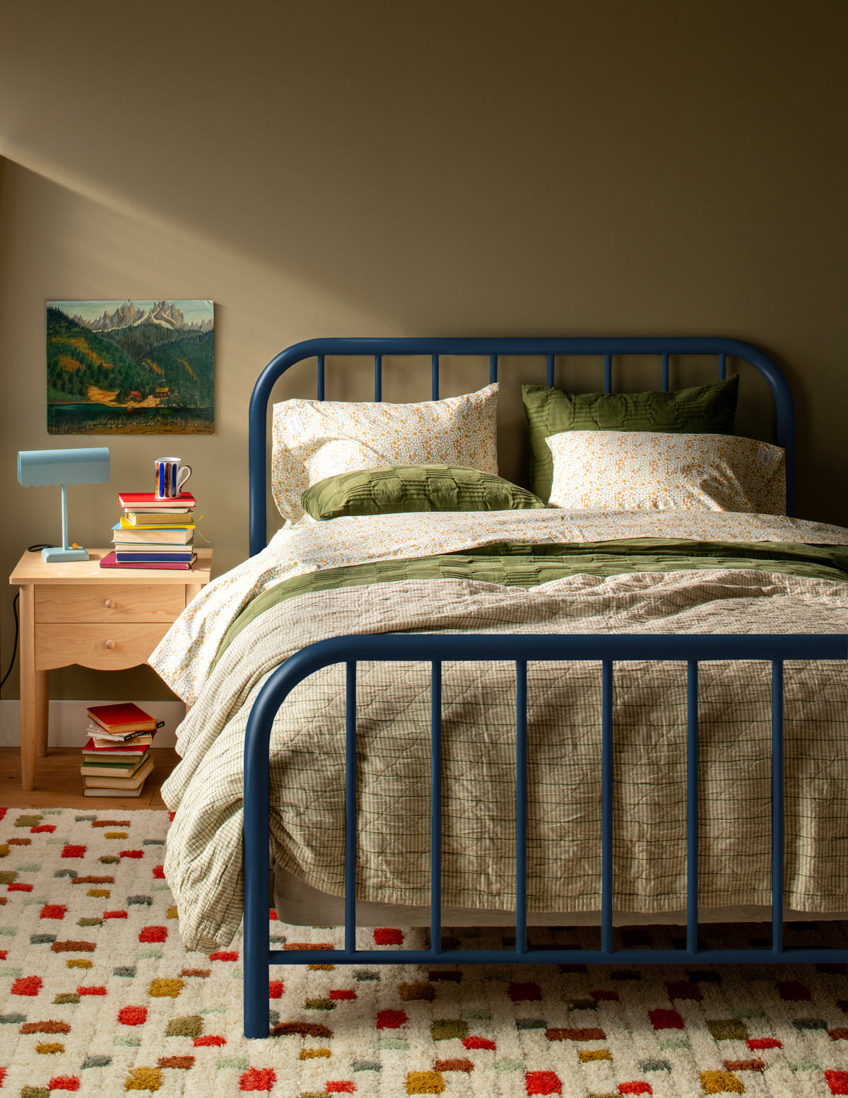 Diamond Ticking Sham pillows arranged on a bed in a warm bedroom with a patterned rug