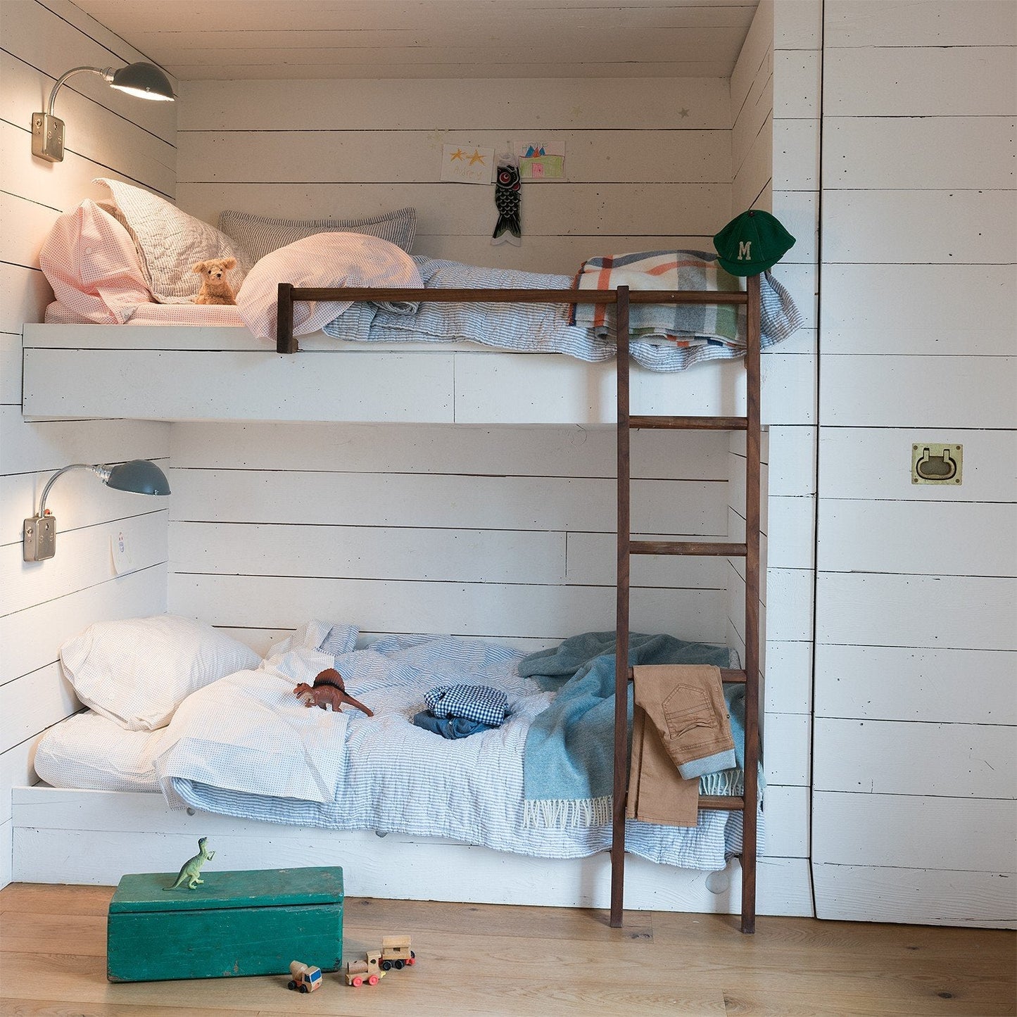 Top-bunk view of Diamond Ticking Quilted Pillow Sham showing quilted ticking texture on pale pink against white plank wall