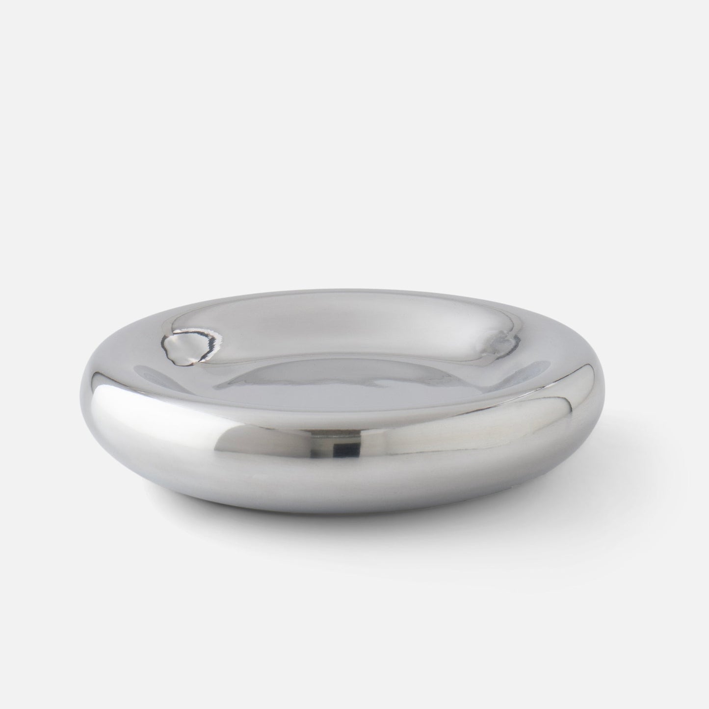 Close-up of Yves cast metal catchall showcasing polished mirrored finish and rounded shallow bowl on white background