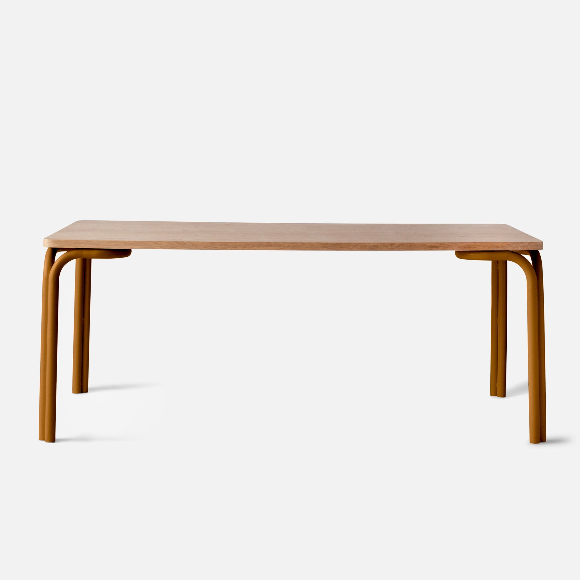 Front view of Forma Dining Table showing light oak tabletop and rounded amber tubular legs on white studio background