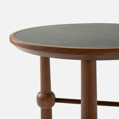 Close-up of Ann Occasional Table showcasing walnut three-leg base and dark green Italian leather top on white background