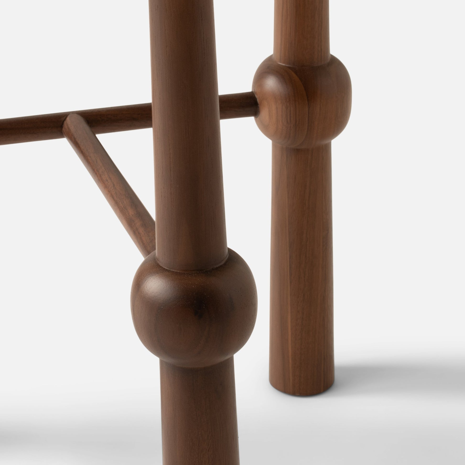 Close-up of Ann occasional table leg showing solid walnut faceted joint and dowel brace on white background