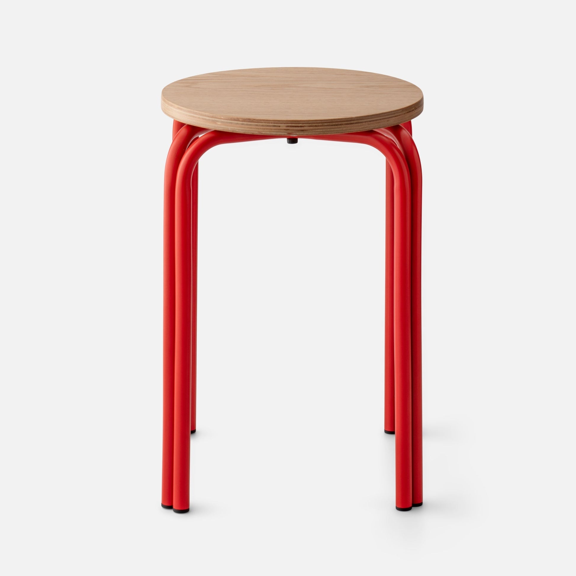 Close-up of Forma Stool showing white oak top with plywood edge and red powder-coated steel legs on white background