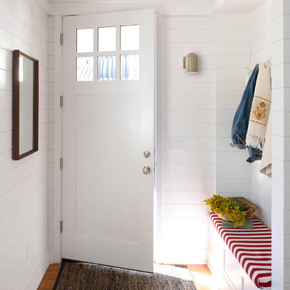 Entryway with open white door and Allegheny lichen gloss wall sconce mounted on white shiplap above a red-and-white striped bench with a denim jacket and basket of yellow flowers