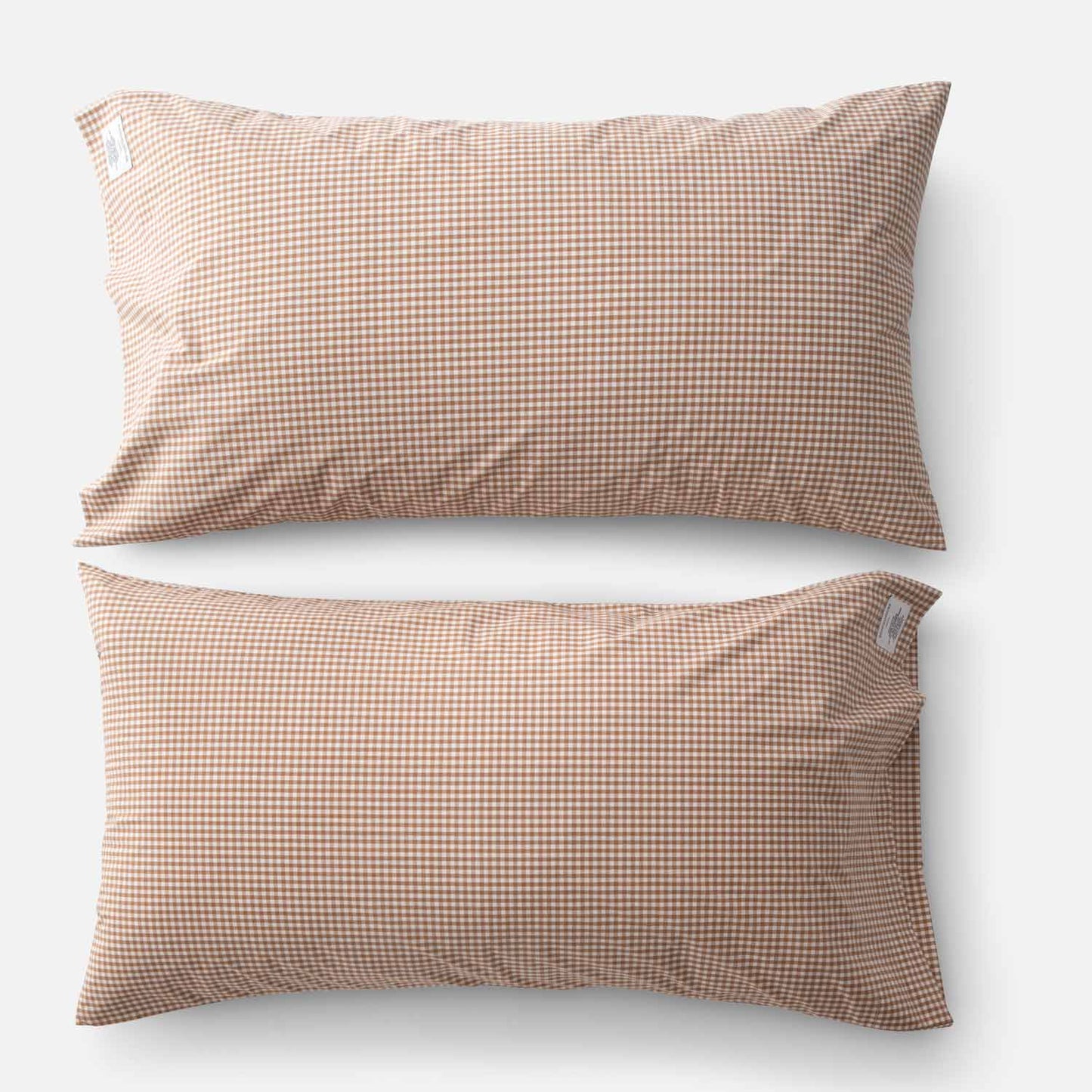 Top-down view of two Gingham percale pillowcases showcasing small tan gingham check on white background