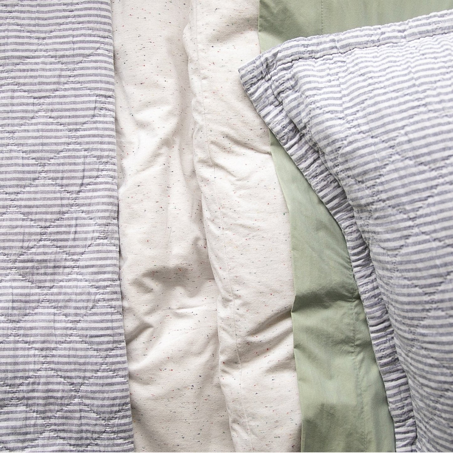 Close-up of Diamond Ticking Quilted Pillow Sham showing gray-and-white ticking stripes on cream and sage bedding