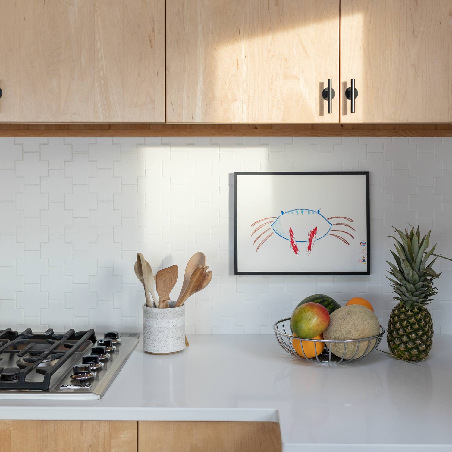Two matte black Galley Pulls mounted on light maple cabinet doors above a white tiled backsplash in a bright kitchen
