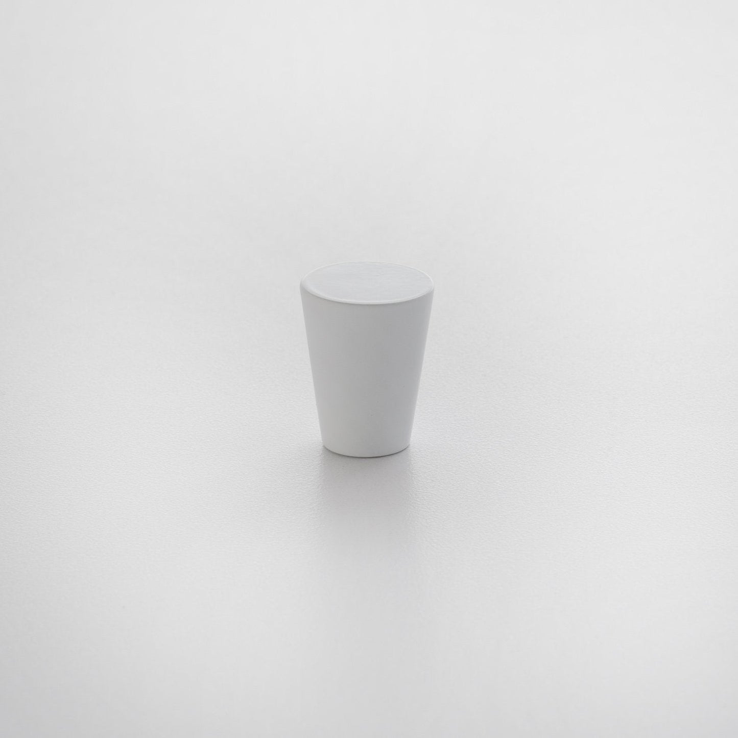 Front view of Newberg knob showcasing tapered conical shape and matte white finish on a light textured background