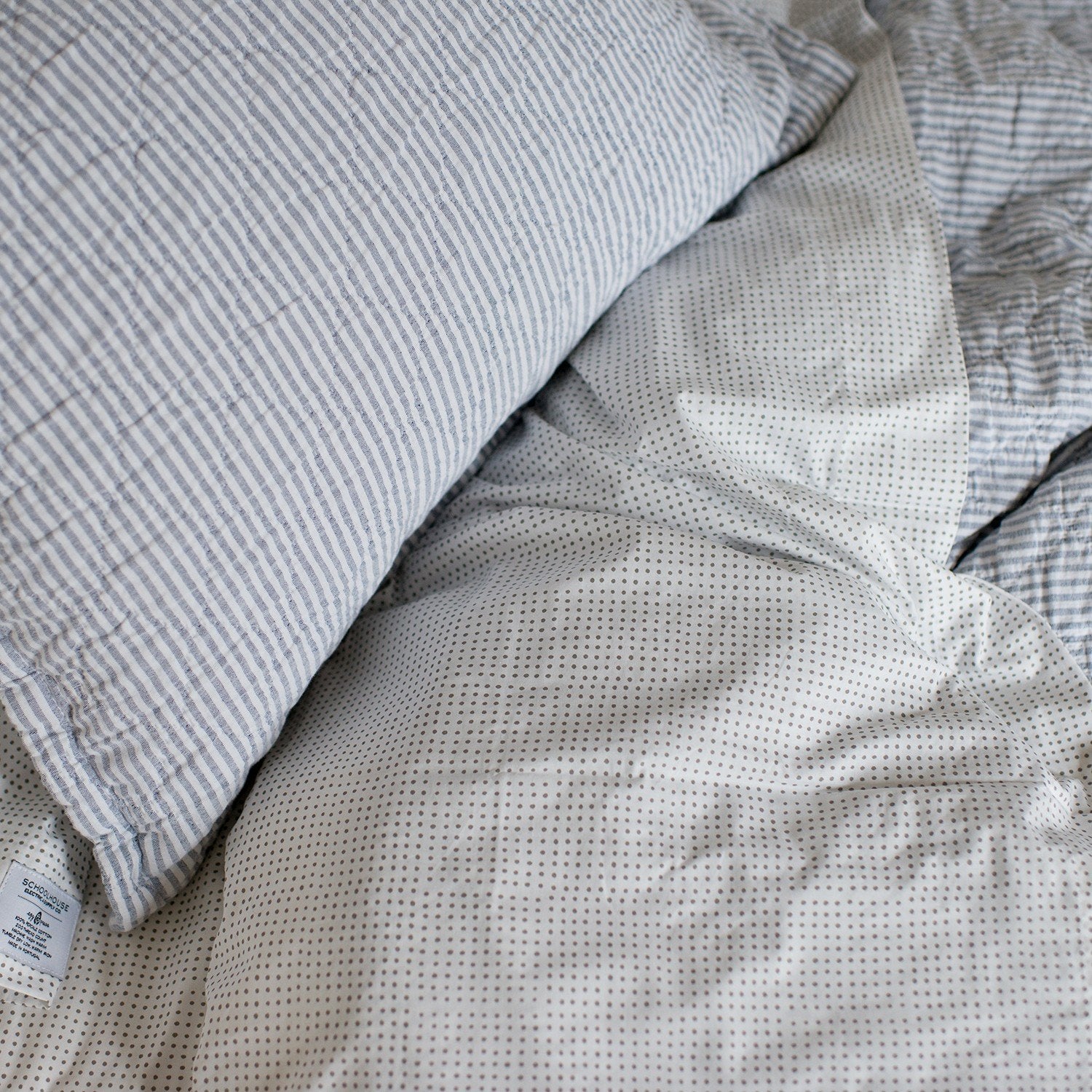Close-up of Diamond Ticking Quilted Pillow Sham showing ticking stripes and diamond quilting on a dotted white sheet