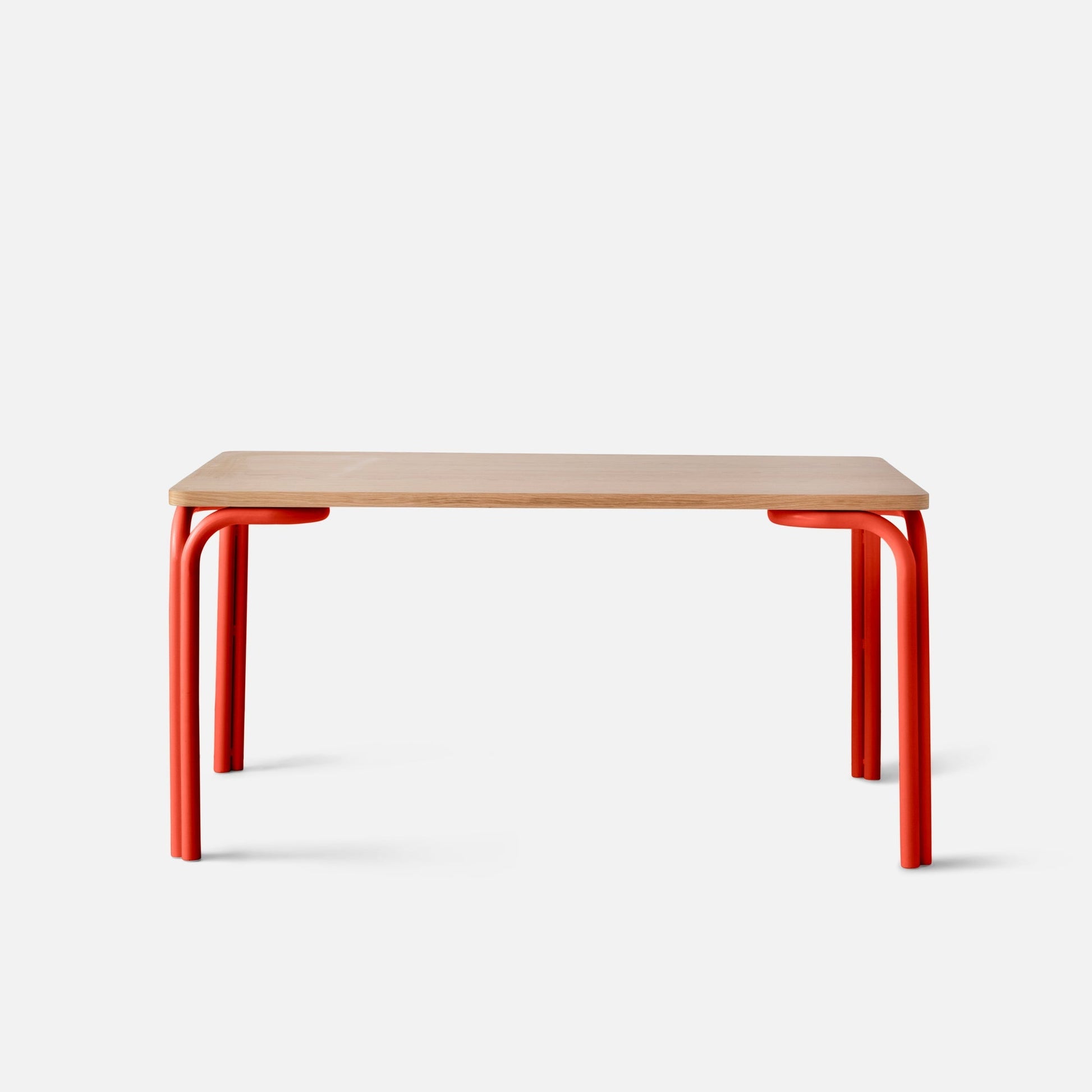 Front view of Forma Dining Table showing light oak top and red tubular metal legs against a white background