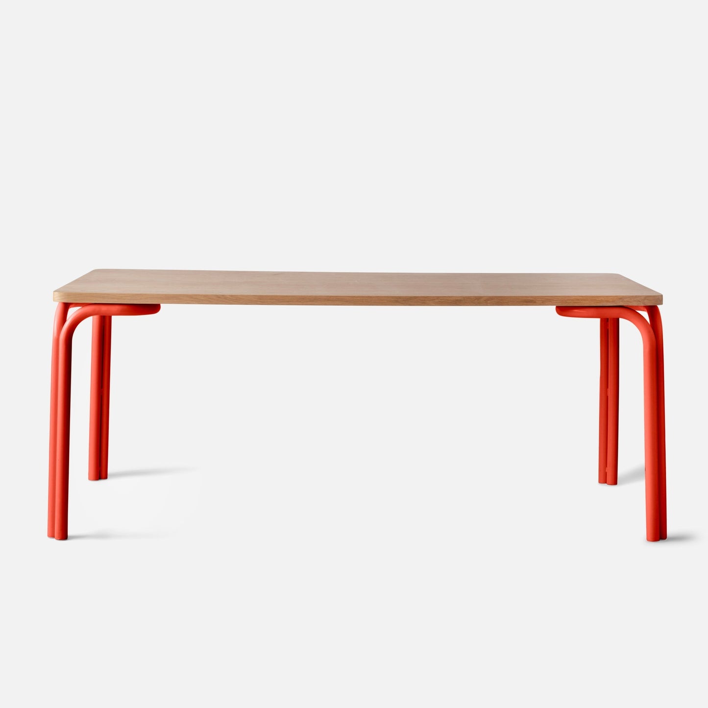 Front view of Forma Dining Table showcasing light oak tabletop and red tubular metal legs on white background