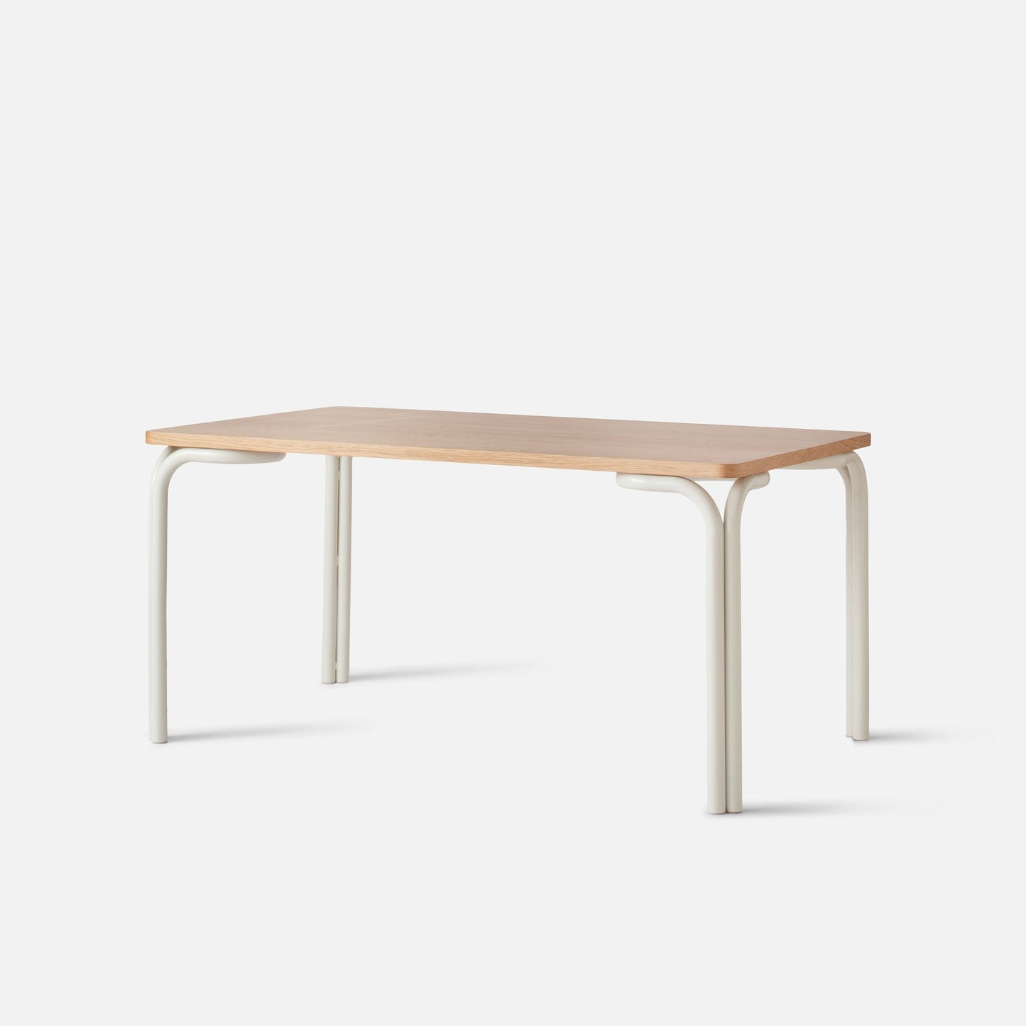 Three-quarter view of Forma Dining Table showcasing light maple tabletop and cream powder-coated curved metal legs on a white studio background