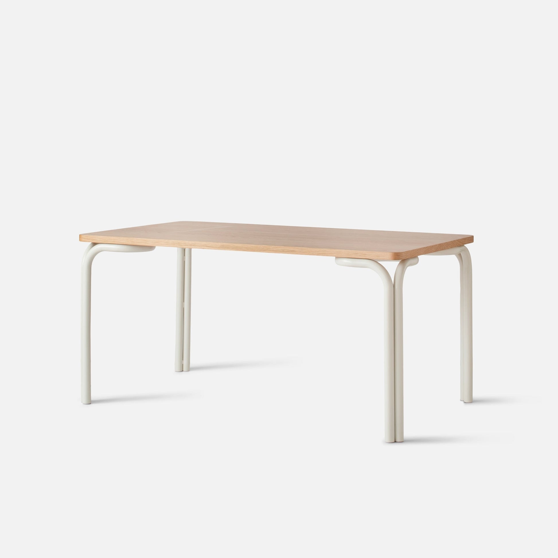 Three-quarter view of Forma Dining Table showcasing light maple tabletop and cream powder-coated curved metal legs on a white studio background